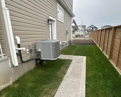 a house with an air conditioner on the side of a yard at Private Very Spacious 2 bed 1-Bedroom basement Suite SW Calgary in Calgary