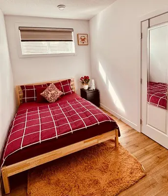 a bedroom with a red bed and a window at Charming Stay & Cozy Retreat by Bansari Homes in Edmonton- YEG in Edmonton