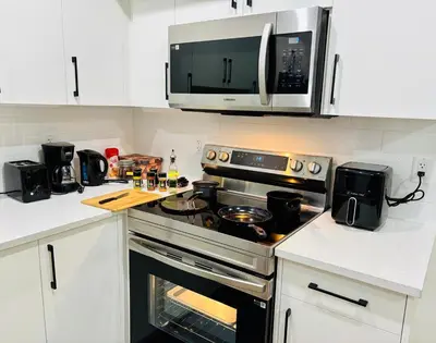 a kitchen with a stove and a microwave at Charming Stay & Cozy Retreat by Bansari Homes in Edmonton- YEG in Edmonton