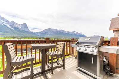 a grill on a deck with a table and chairs at Breathtaking Luxury 3Bd Penthouse Pool and Hot Tub in Canmore