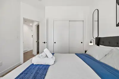 a bedroom with a large bed with towels on it at Luxury Aspen 2BR Home with Double Garage Car Parking in Calgary