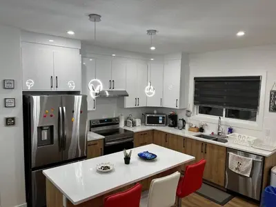 a kitchen with a refrigerator and a table with red chairs at Elegant 3BD Home in Beaumont, Double Garage in Nisku