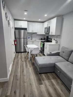 a living room with a couch and a table and a kitchen at lovely 2bed & 1 Bath Basement Suite for 4 guests in Calgary