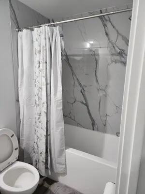 a bathroom with a white toilet and a shower at lovely 2bed & 1 Bath Basement Suite for 4 guests in Calgary