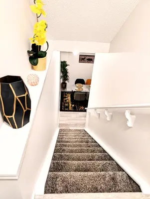 a staircase leading up to a living room with yellow flowers at Luxury Modern 2-Bedroom Suite in Airdrie