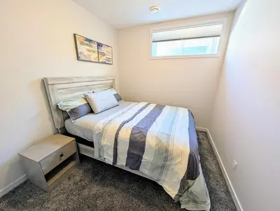 a small bedroom with a bed and a window at Luxury Modern 2-Bedroom Suite in Airdrie