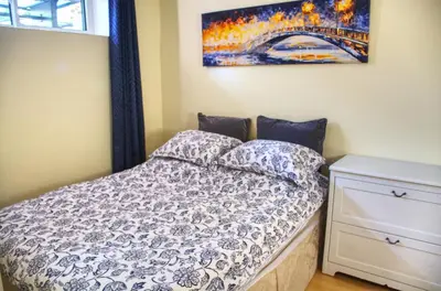 a bedroom with a bed and a painting on the wall at Calm, cozy, urban, family-friendly stay in Vancouver