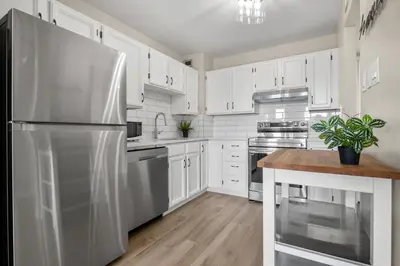 a kitchen with white cabinets and a stainless steel refrigerator at Winter Prices Reduced for Stylish Condo & Easy to Mountains ! in Calgary