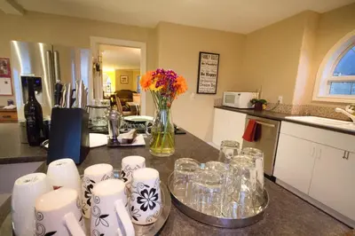 a kitchen with a table with glasses and a vase of flowers at Eagle Close Executive B&B in Prince Rupert