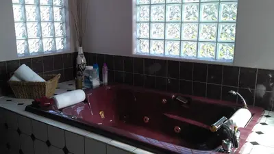 a red bath tub in a bathroom with windows at Eagle Close Executive B&B in Prince Rupert