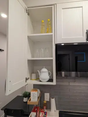 a kitchen with white cabinets and a microwave at MIAT Apartment in Calgary