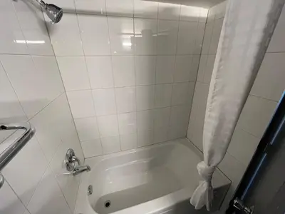 a bathroom with a tub with a shower curtain at The Lodge Inn in Edmonton