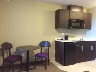 a small kitchen with a table and chairs and a counter at Meridian Inn & Suites Lloydminster in Lloydminster
