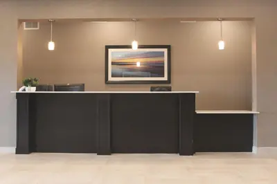 a lobby with a black counter with a picture on the wall at Meridian Inn & Suites Lloydminster in Lloydminster