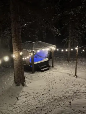 a gazebo with lights in the snow at night at Rustic Cozy Cabin with hot tub in Bragg Creek