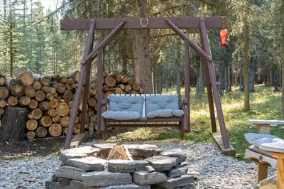 a swing in a yard next to a pile of logs at Shanti Yurt with private hot tub in Bragg Creek in Bragg Creek