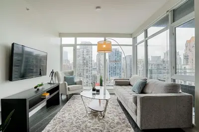 a living room with a couch and a tv at Modern Downtown Apartment with Water Views in Vancouver