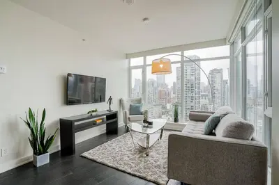 a living room with a couch and a tv at Modern Downtown Apartment with Water Views in Vancouver
