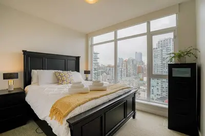 a bedroom with a bed and a large window at Modern Downtown Apartment with Water Views in Vancouver