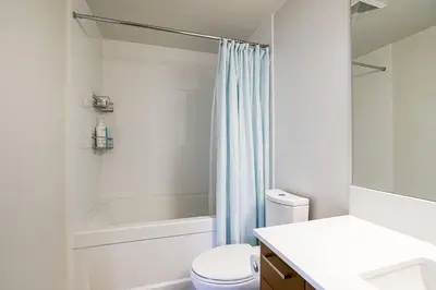 a white bathroom with a toilet and a shower at Modern Downtown Apartment with Water Views in Vancouver