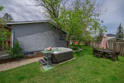 a hot tub in a yard with a table and chairs at Dreams off 16th in Calgary