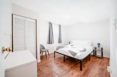 a white bedroom with a bed and a chair at Dreams off 16th in Calgary