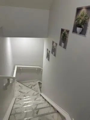 a white bathroom with pictures on the wall and a glass floor at The Modern Nest-one bedroom basement suite in Calgary