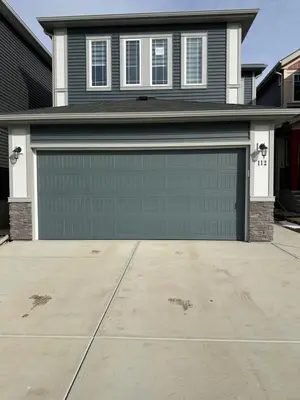 a house with a green garage door on a driveway at The Modern Nest-one bedroom basement suite in Calgary