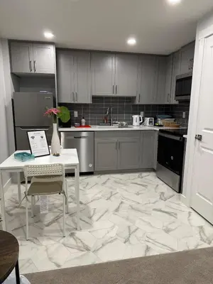 a kitchen with a white table and a white floor at The Modern Nest-one bedroom basement suite in Calgary