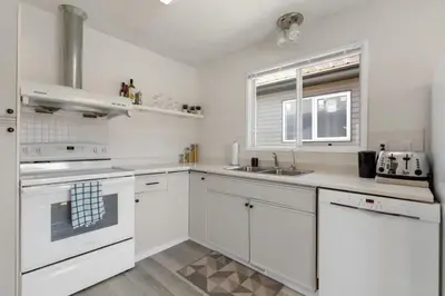 a white kitchen with white cabinets and a sink at Hoodoo Hideout - 2BR House - Family Retreat - King Suite in Drumheller