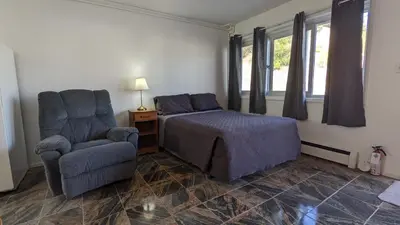 a bedroom with a bed and a chair at Deerview Lodge & Cabins - Princeton BC in Princeton