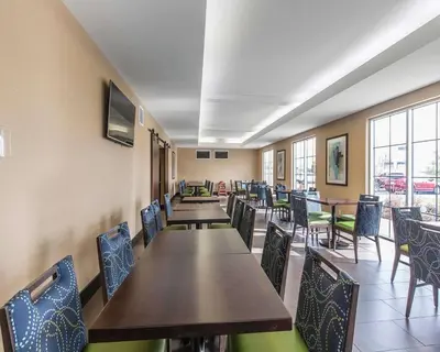 a dining room with tables and chairs and windows at Comfort Inn & Suites Airport North in Calgary