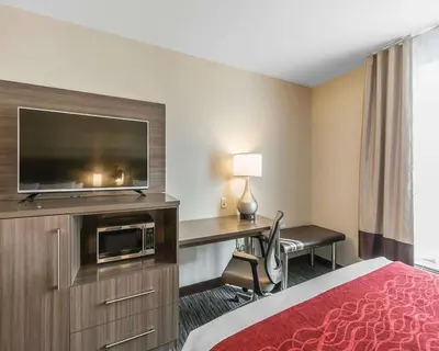 a hotel room with a bed and a desk with a television at Comfort Inn & Suites Airport North in Calgary