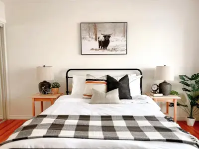 a bedroom with a bed with a black and white checked blanket at Modern 3BR Near Airport & DT in Calgary