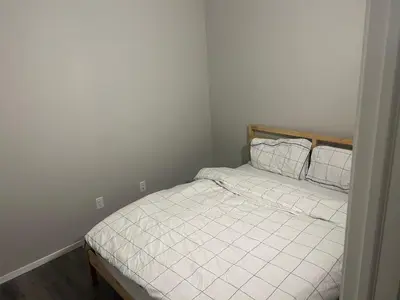 a bedroom with a bed with white sheets and pillows at Basement Suite Near Edmonton Airport YEG in Edmonton