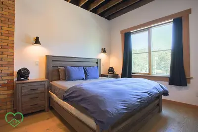 a bedroom with a large bed and a window at Downtown Loft with Rooftop Hot Tub by StayIn in Fernie