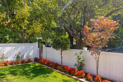 a white fence with red flowers in a yard at Vancouver Cozy Cove in Vancouver