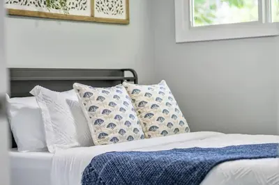 a white bed with blue and white pillows on it at The Experience - Pool Hot Tub Theater Games Rm Pub in Calgary