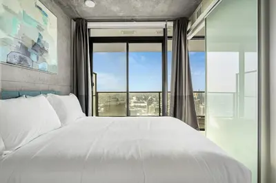 a bedroom with a white bed and a large window at Executive Sky LUX - 2 BD 2BA Views Pool Patio & Gym in Calgary