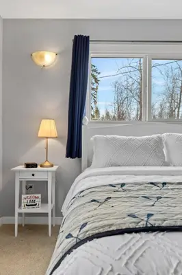 a bedroom with a white bed and a window at Lake Vibes 3 BD 1 BA Cottage steps from the Lake in Lacombe