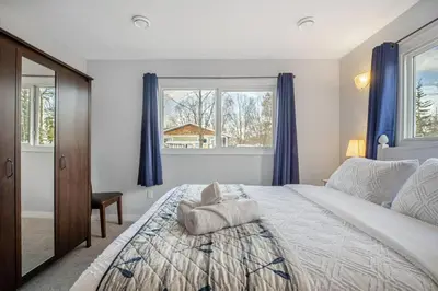 a bedroom with a large bed with blue curtains at Lake Vibes 3 BD 1 BA Cottage steps from the Lake in Lacombe