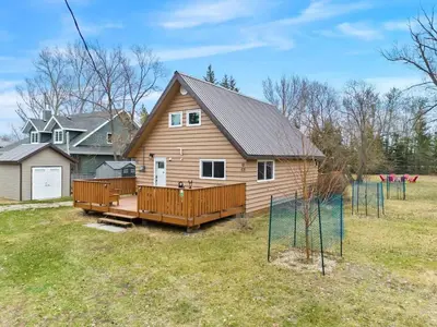 a large wooden house with a large deck at Lake Vibes 3 BD 1 BA Cottage steps from the Lake in Lacombe