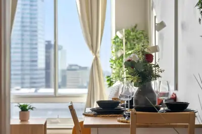 a dining room table with a vase of flowers and a window at Eminence Sleek Studio City View in Edmonton