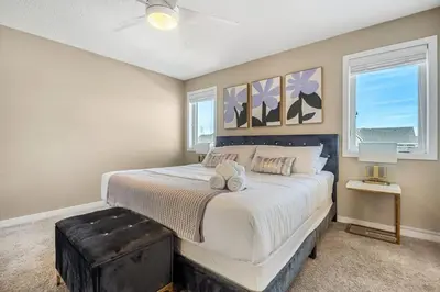 a bedroom with a large bed and two windows at The Trenta - 4BD 3BA 2 Kitchen Stunner in Calgary