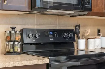 a stove top oven in a kitchen with a microwave at The Grande 1BD 1BA - Full Kitchen Guest Suite in Calgary