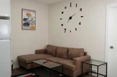 a living room with a couch and a clock on the wall at Cozzy Cityscape & Airport Retreat in Calgary