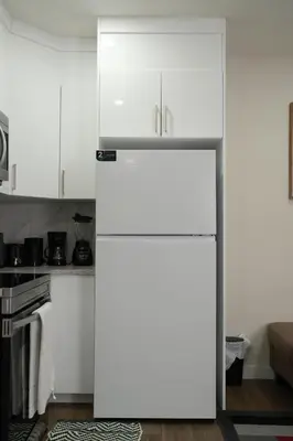a refrigerator in a kitchen with white cabinets at Cozzy Cityscape & Airport Retreat in Calgary