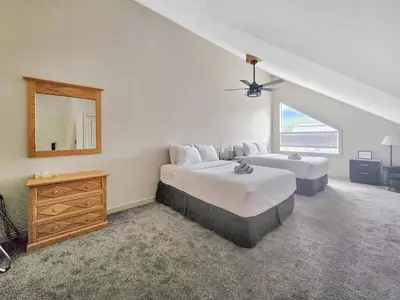 a bedroom with two beds and a dresser and a mirror at Riverside Way by Fernie Lodging Company in Fernie