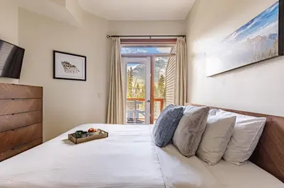 a bedroom with a bed with white sheets and a window at Mountain Luxe - 50 Percent Off April & May in Canmore