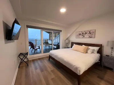 a bedroom with a large bed and a balcony at Top FL 2BR 2BA Hot Tubs phenomenal mountain views in Canmore